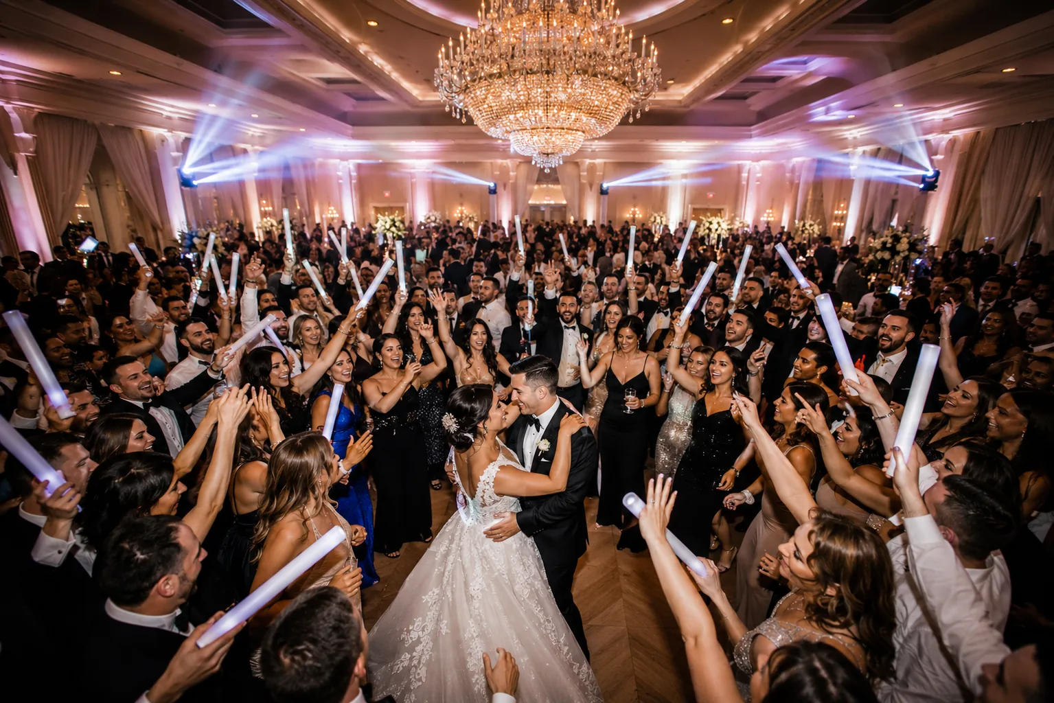 Bride and groom sharing a kiss on a packed dance floor surrounded by cheering guests at a Hot Mix Entertainment wedding